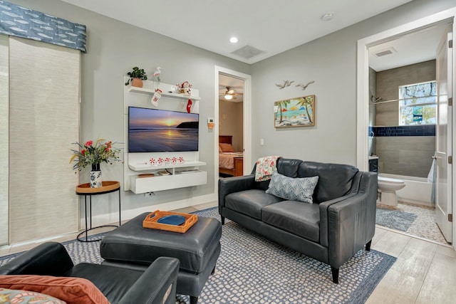 living room with light wood-style floors, visible vents, ceiling fan, and baseboards