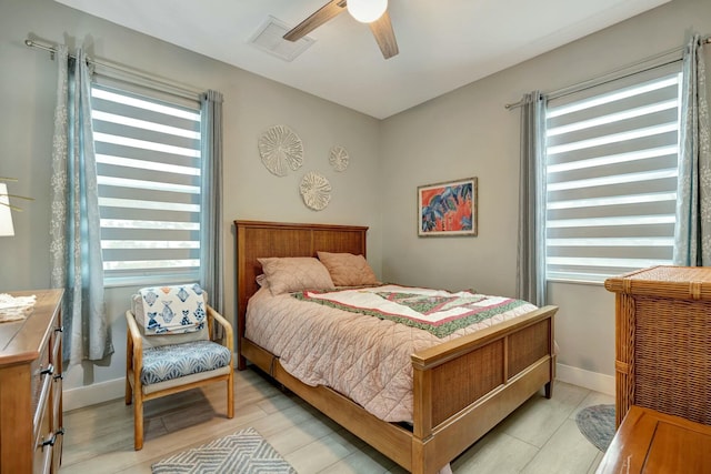 bedroom featuring light wood-style floors, baseboards, visible vents, and a ceiling fan