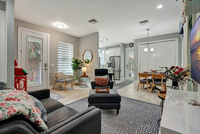 living room with a notable chandelier and light wood-type flooring