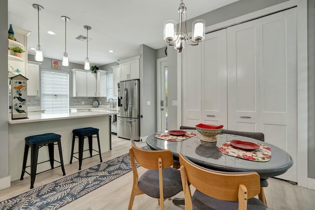 dining space featuring recessed lighting, light wood-type flooring, visible vents, and an inviting chandelier