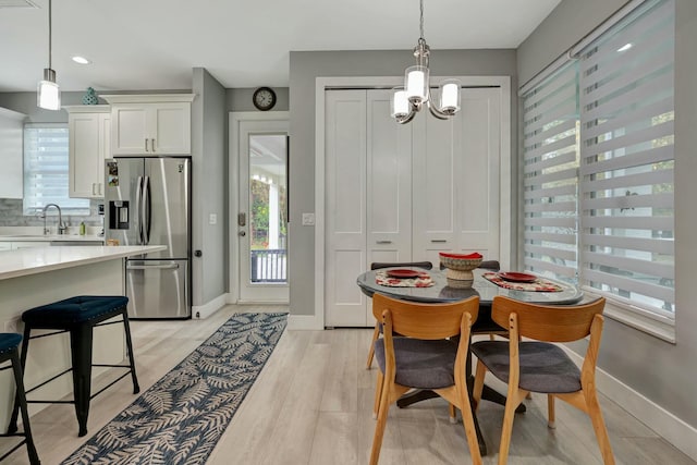 dining area with baseboards, an inviting chandelier, and light wood-style floors