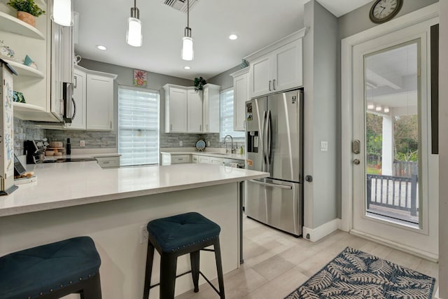 kitchen with stainless steel appliances, a peninsula, light countertops, open shelves, and tasteful backsplash