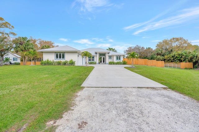 view of front facade featuring fence, metal roof, concrete driveway, and a front yard