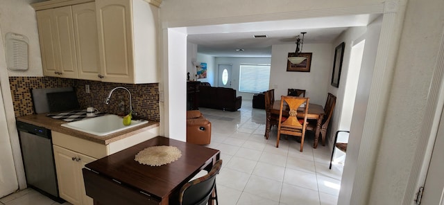 kitchen featuring stainless steel dishwasher, cream cabinets, light tile patterned floors, decorative backsplash, and sink