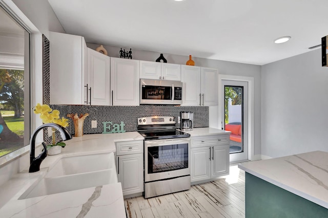 kitchen featuring backsplash, appliances with stainless steel finishes, sink, and white cabinets