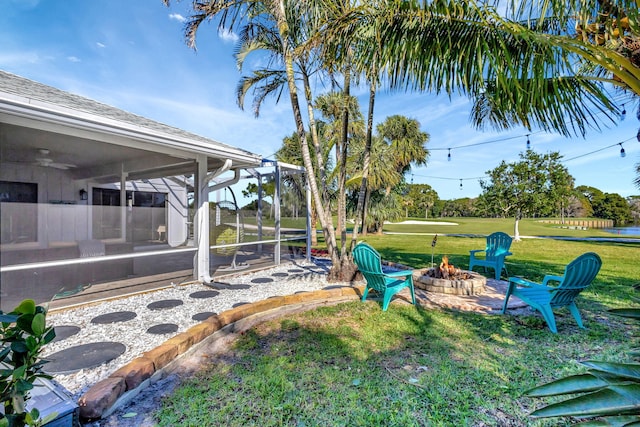 view of yard featuring a sunroom, glass enclosure, and a fire pit