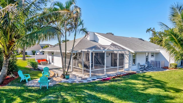 rear view of property with a fire pit, a yard, a patio area, and glass enclosure