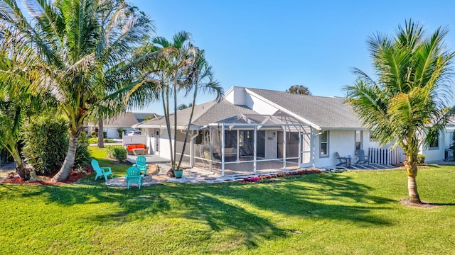 rear view of house with a lanai, a lawn, and a patio