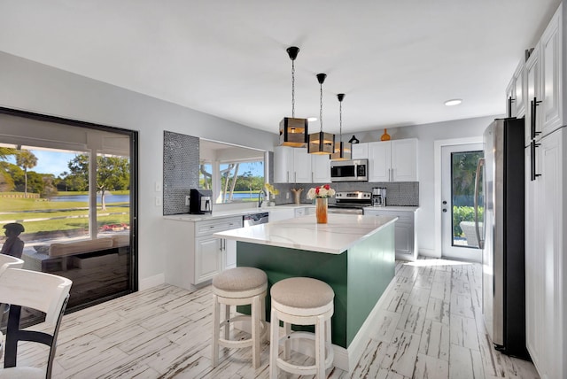 kitchen with white cabinetry, appliances with stainless steel finishes, a kitchen breakfast bar, and a kitchen island