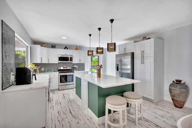 kitchen featuring white cabinetry, decorative backsplash, a kitchen island, and appliances with stainless steel finishes