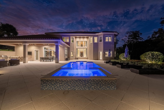 pool at dusk with a patio, ceiling fan, and an in ground hot tub