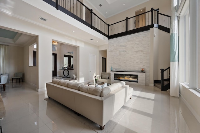 tiled living room with a high ceiling, a large fireplace, and a healthy amount of sunlight