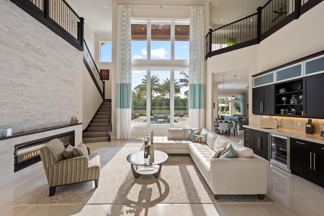 tiled living room with indoor wet bar, beverage cooler, a towering ceiling, and a fireplace