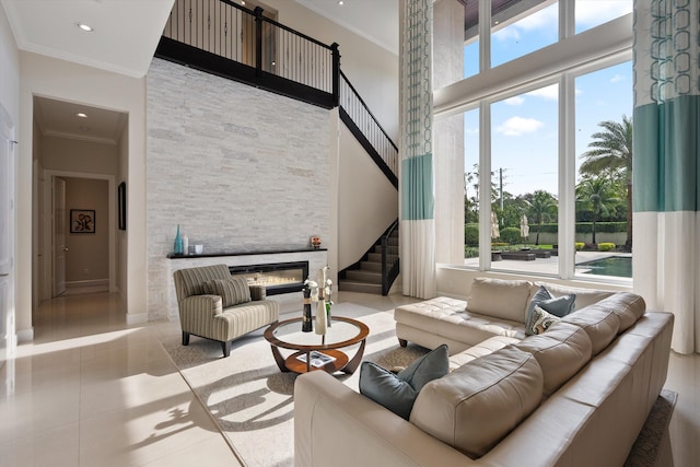 tiled living room with a towering ceiling, ornamental molding, and a stone fireplace