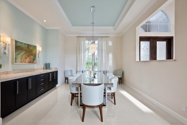 tiled dining area with a chandelier, ornamental molding, and a raised ceiling