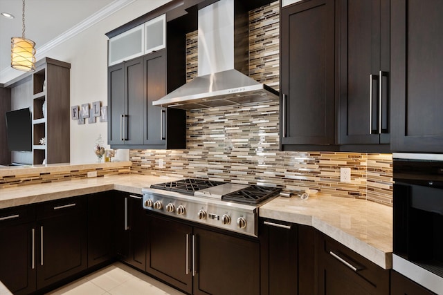 kitchen featuring backsplash, butcher block countertops, hanging light fixtures, ornamental molding, and wall chimney exhaust hood