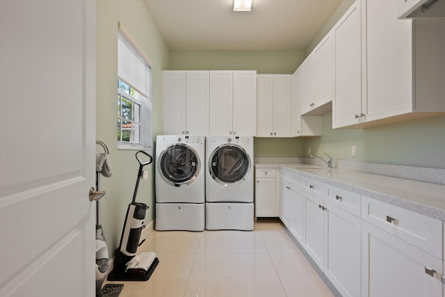 laundry area featuring light tile patterned floors, cabinets, washer and clothes dryer, and sink