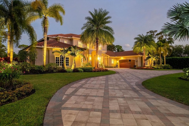 mediterranean / spanish-style home with a garage and a yard