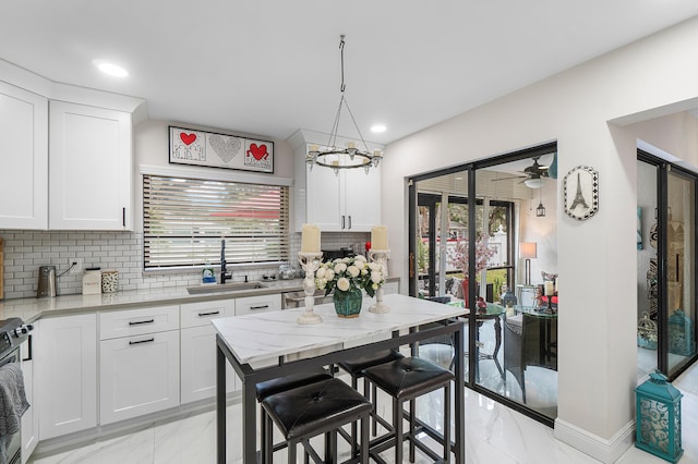 kitchen with light stone counters, white cabinets, a breakfast bar, and sink