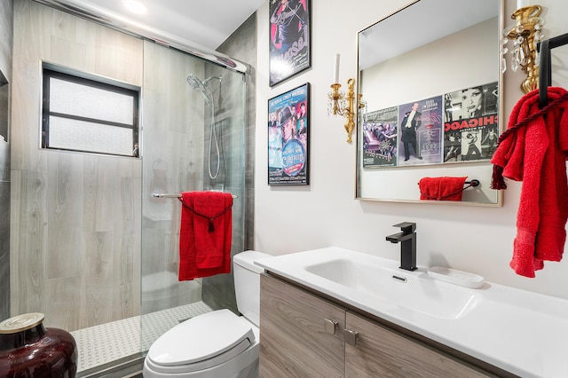 bathroom featuring toilet, a shower with door, and vanity