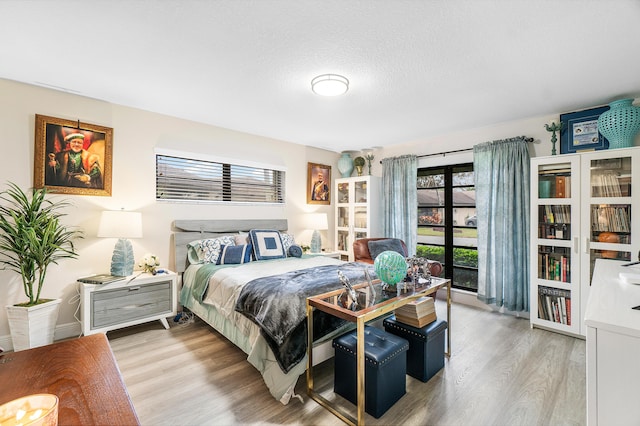 bedroom with a textured ceiling and light hardwood / wood-style flooring