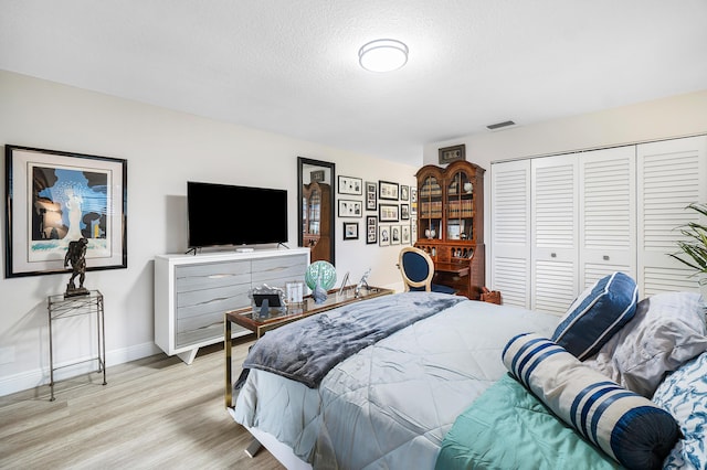 bedroom with a textured ceiling, a closet, and light hardwood / wood-style flooring