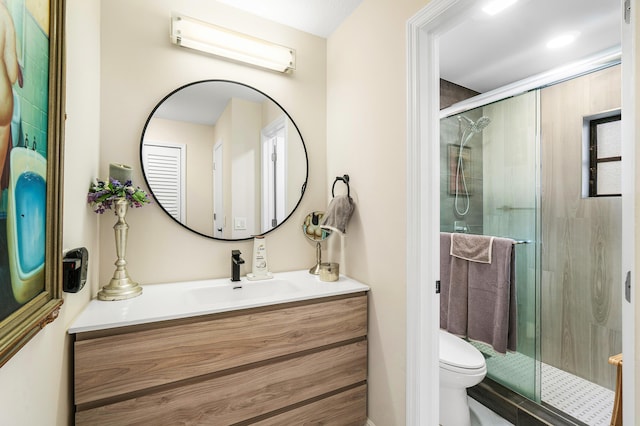 bathroom featuring toilet, a shower with door, and vanity