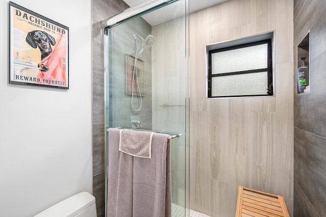 bathroom featuring toilet and a shower with shower door