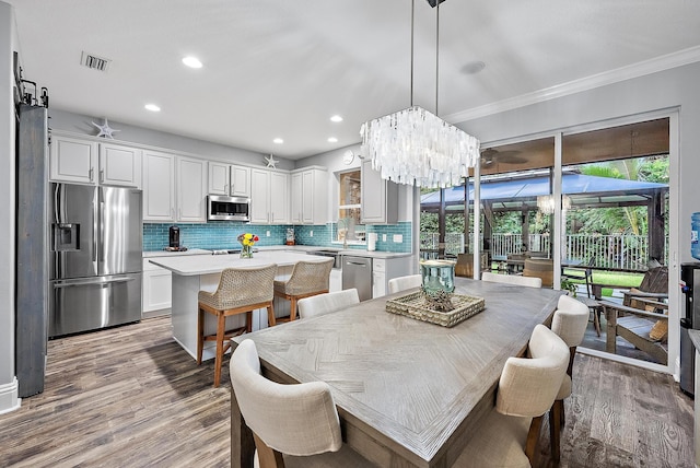 dining space with ornamental molding, an inviting chandelier, and light hardwood / wood-style floors