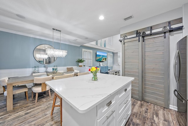 kitchen with white cabinets, a center island, hanging light fixtures, a barn door, and dark wood-type flooring