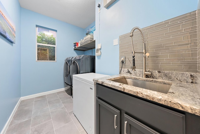 washroom with a textured ceiling, washer and clothes dryer, cabinets, light tile patterned flooring, and sink