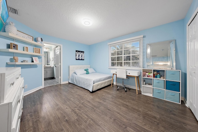 bedroom with ensuite bathroom, a closet, a textured ceiling, and dark hardwood / wood-style floors