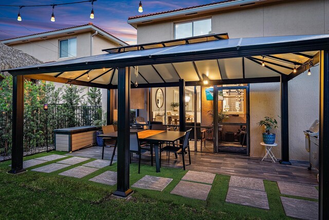 back house at dusk featuring a patio and a gazebo