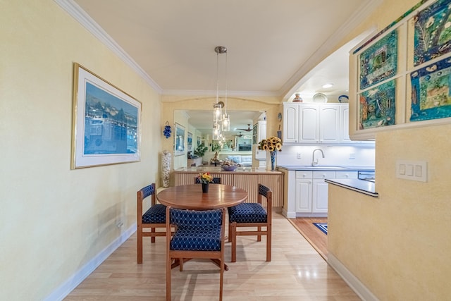 dining area with sink, crown molding, and light hardwood / wood-style floors