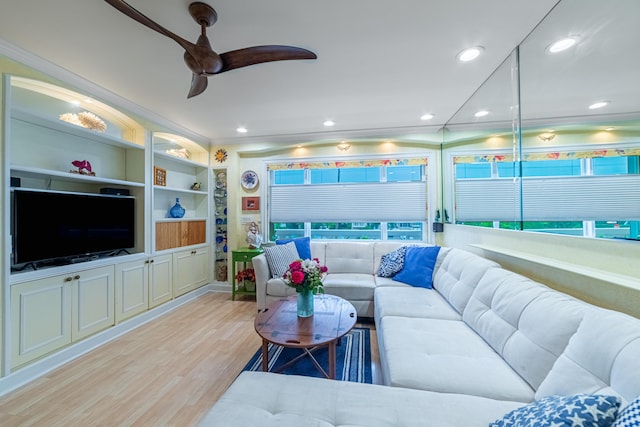 living room featuring ceiling fan, light wood-type flooring, built in features, plenty of natural light, and ornamental molding