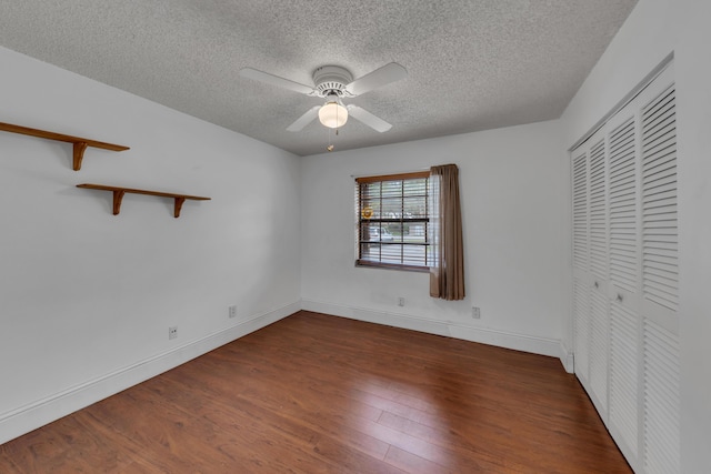 unfurnished bedroom with ceiling fan, dark wood-type flooring, a closet, and a textured ceiling