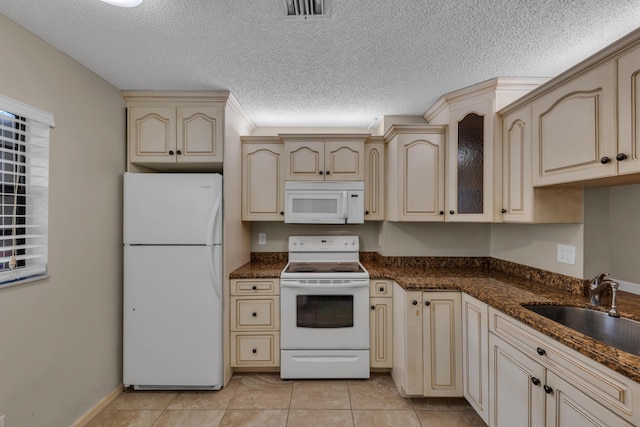 kitchen with sink, white appliances, cream cabinetry, and light tile patterned flooring