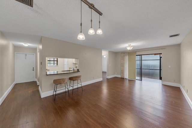 living room featuring sink, a textured ceiling, and dark hardwood / wood-style flooring