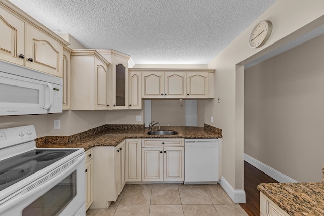 kitchen featuring white appliances, cream cabinets, sink, and dark stone countertops