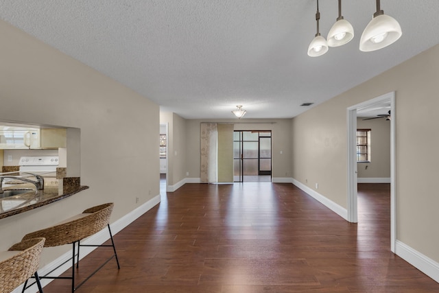 living room featuring sink, dark wood-type flooring, and a textured ceiling