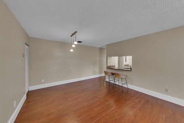 unfurnished living room featuring dark hardwood / wood-style flooring and a textured ceiling