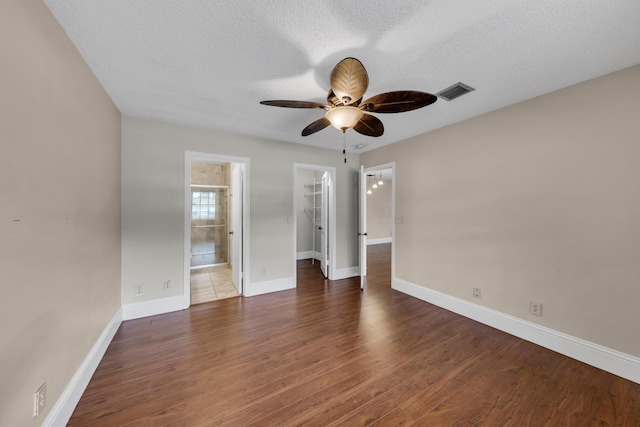 unfurnished bedroom featuring a spacious closet, a textured ceiling, dark hardwood / wood-style floors, and a closet