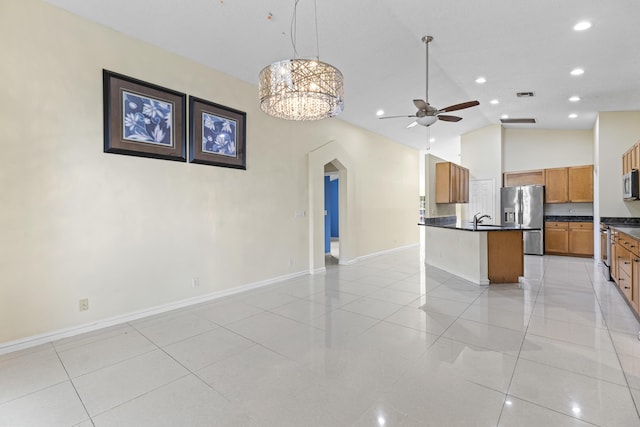 kitchen with appliances with stainless steel finishes, hanging light fixtures, sink, an island with sink, and ceiling fan with notable chandelier