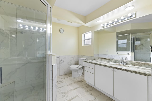 bathroom with vanity, toilet, tile walls, and a shower with door