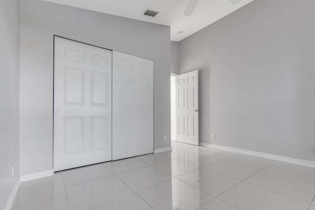 unfurnished bedroom with ceiling fan, light tile patterned floors, and a closet