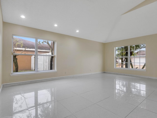 tiled empty room with vaulted ceiling and a wealth of natural light