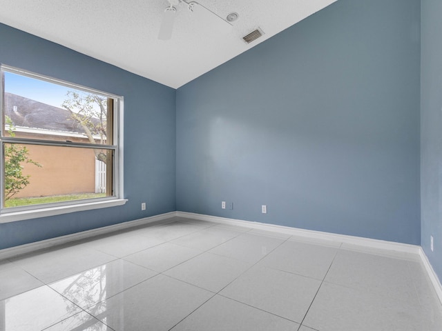 tiled spare room featuring ceiling fan, a textured ceiling, and lofted ceiling