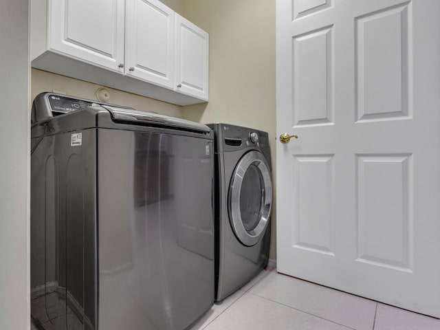 laundry room featuring independent washer and dryer, cabinets, and light tile patterned floors