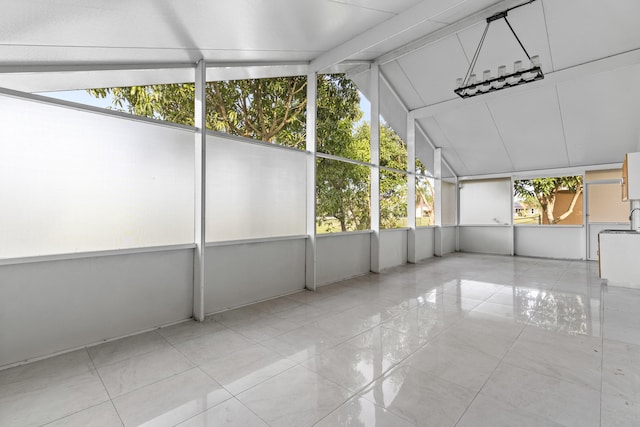 unfurnished sunroom featuring vaulted ceiling with beams