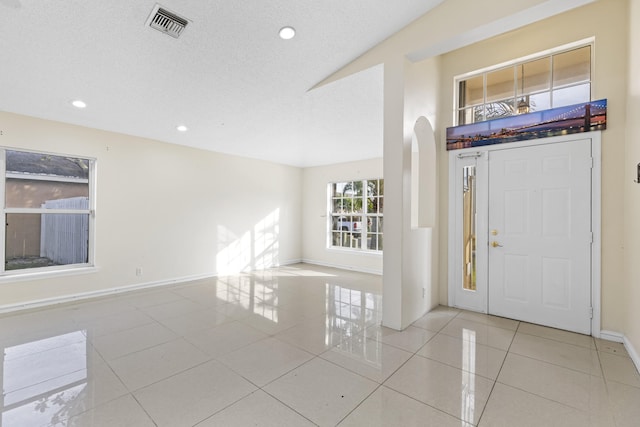 foyer with a textured ceiling and light tile patterned flooring